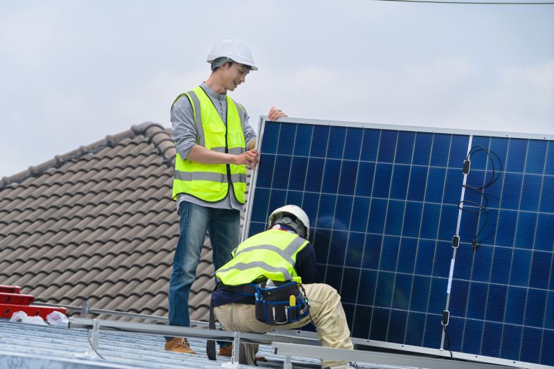 Due installatori montano un pannello fotovoltaico sul tetto di una casa