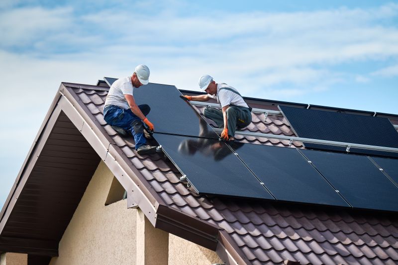 Due installatori montano i pannelli fotovoltaici sul tetto di una casa