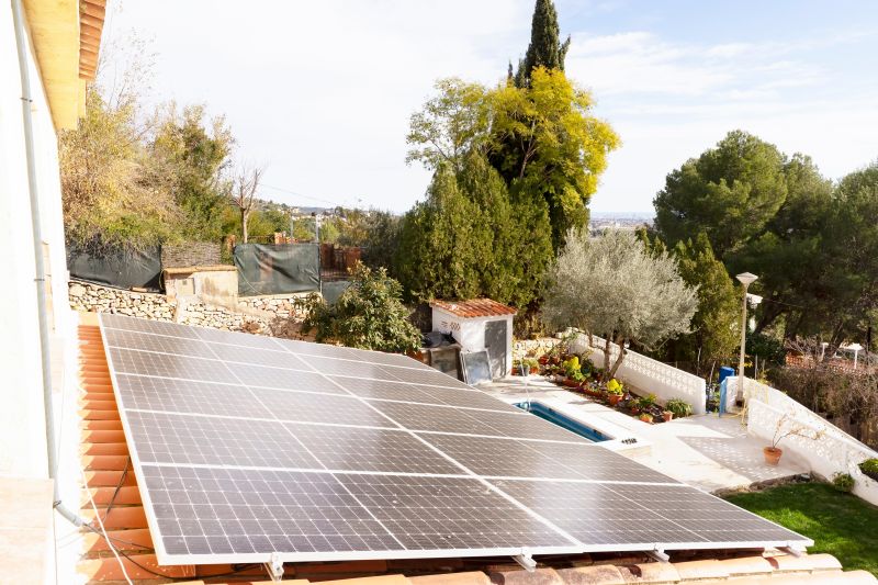 Pannelli fotovoltaici sul tetto in coppi di una casa con giardino